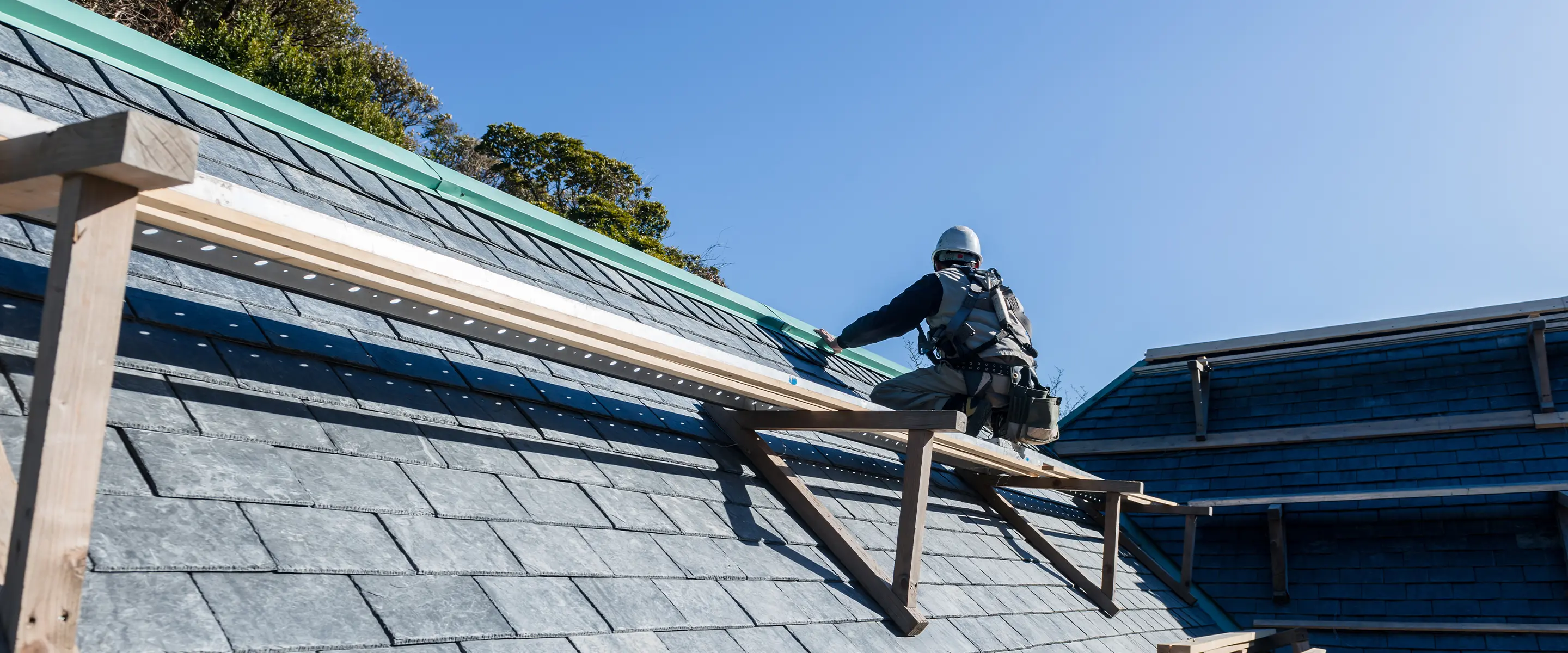 屋根の上で工事をする職人